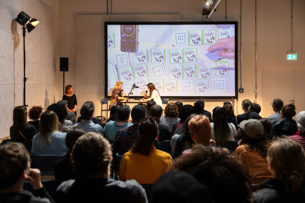 Menschen schauen auf eine Bühne, wo zwei Personen Memory spielen